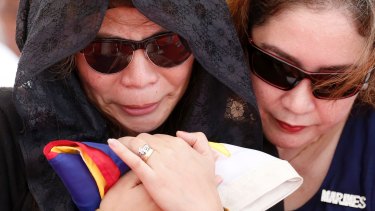 Leslie Abad, left, the widow of First Lieutenant Raymond Abad of the Philippine marines, holds the national flag during his burial on Tuesday.  Abad was one of the 13 marines killed in fighting between government forces and Muslim militants in Marawi.