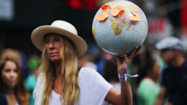 On the sidelines: A protester takes part in a climate change march in New York earlier this year. The Abbott government is "looking more and more sad, greedy and isolated" on the issue of climate change, Greens leader Christine Milne says.