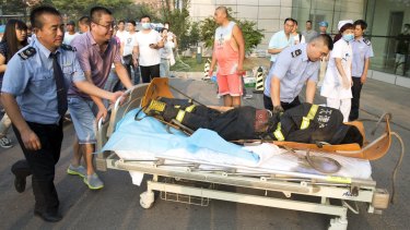 Security guards and a resident push a victim into a hospital in Tianjin early Thursday.