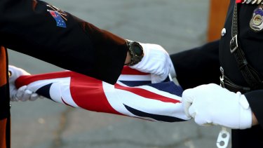Australian police officers fold the Australian flag during a flag-lowering ceremony. in Nicosia, Cyprus.