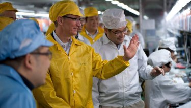 Apple Chief Executive Officer Tim Cook (2nd L) talks to employees as he visits the iPhone production line at the newly built Foxconn Zhengzhou Technology Park, in 2012.