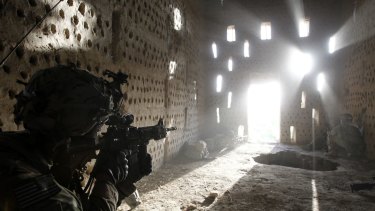 A US soldier points his rifle at a doorway after coming under fire by the Taliban in southern Kandahar province, one of the Taliban's strongholds.