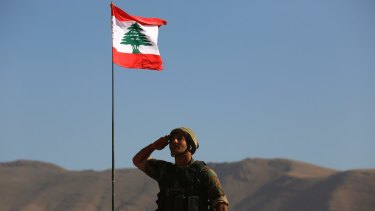 A Lebanese soldier salutes the national flag atop an armoured personnel carrier on the outskirts of Ras Baalbek, north-east Lebanon on Monday.