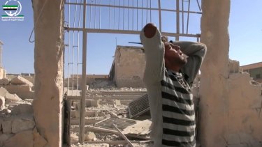 A man wails in front of destroyed buildings after airstrikes killed more than 20 people, in the northern rebel-held village of Hass, Syria, on Wednesday.