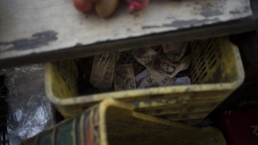 A crate filled with 100-bolivar notes sits under the counter of a fruit stand in Caracas.