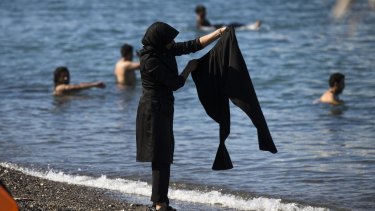 A migrant woman washes trousers at an unofficial migrant tent camp on a beach on the island of Kos, Greece.