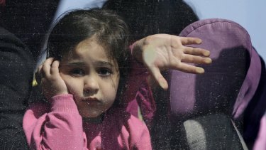 A girl looks out of a bus window after arriving by ferry with hundreds of other migrants at the Greek port of Elefsina on Monday. 
