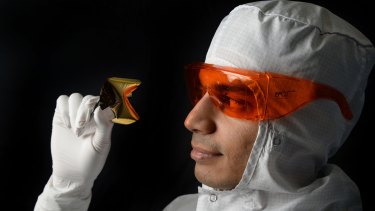 Associate Professor Sharath Sriram, pictured with an optical chip, must wear a protective suit when working in the lab.