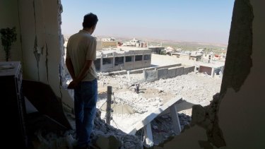 A man looks out from a ruined building in the Syrian town of al-Hara, in the southern province of Daraa, at what activists said was a site hit by barrel bombs dropped by government forces.