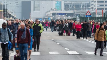 People walk away from Brussels airport after the blasts.