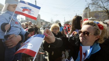 A woman distributes flags during a theatrical performance in Simferopol on Saturday to mark the first anniversary of Russia's annexation the Crimean Peninsula.