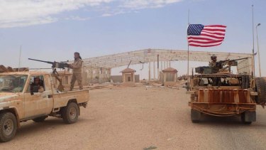 A US-backed anti-government Syrian fighter stands on a vehicle next to an American soldier who also stands on his armoured vehicle, right, as they take their position at the Syrian-Iraqi crossing border point of Tanf, south Syria. 