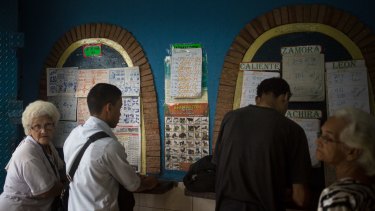 Customers view the animal lottery board before purchasing tickets in Caracas.