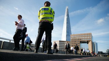 Commuters walk past a police officer on London Bridge on Monday.