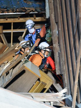 Firefighters speak to a resident trapped inside a house destroyed by Thursday's earthquake in Mashiki, Kumamoto prefecture, southern Japan.