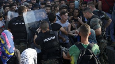 Police officers confront migrants at the railway station in Gevgelija.  