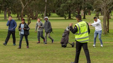 A security guard removes Pokemon Go gamers while a golfer hits his ball on the Glen Waverley Golf Course.