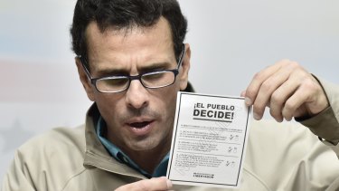 Henrique Capriles, opposition leader and governor of the State of Miranda, holds a voting card as he speaks during a press conference in Caracas.
