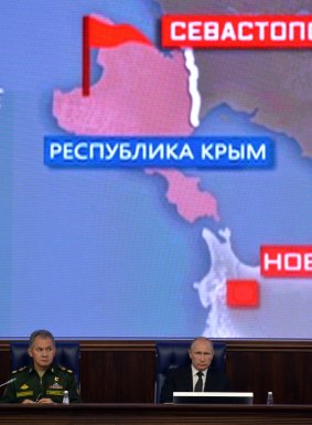 Russian President Vladimir Putin (right) and Defence Minister Sergei Shoigu sit in front of a map of the Crimean Peninsula at a defence ministry meeting on Friday.