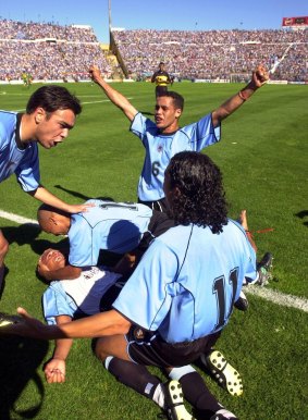 Uruguay's Dario Silva, on the ground, is embraced by teammates after scoring Uruguay's first goal.