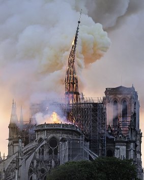 Flames and smoke rise as the spire on Notre Dame cathedral collapses in Paris, Monday, April 15, 2019. Massive plumes of yellow brown smoke is filling the air above Notre Dame Cathedral and ash is falling on tourists and others around the island that marks the center of Paris. (AP Photo/Diana Ayanna)