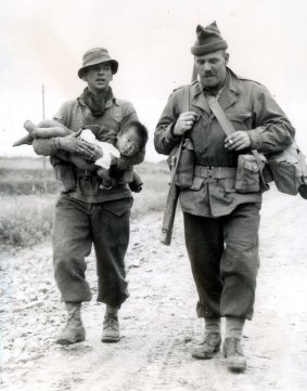 Two Diggers bring in a wounded Korean child for medical treatment.