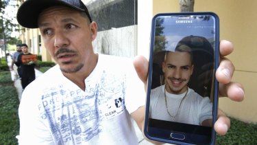 Angel Mendez, outside the Orlando Regional Medical Centre, holds up a phone photo trying to get information about his brother Jean C. Mendez who was at the Pulse Nightclub.