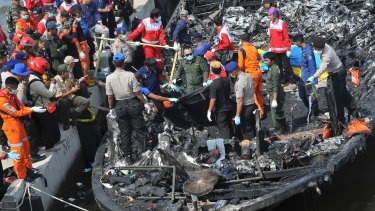 Rescuers search for victims from the wreckage of a ferry that caught fire off the coast of Jakarta.