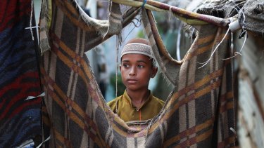 A young Rohingya boy looks out from a torn blanket used as a wall at a temporary shelter on the outskirts of Jammu, India, o Wednesday.
