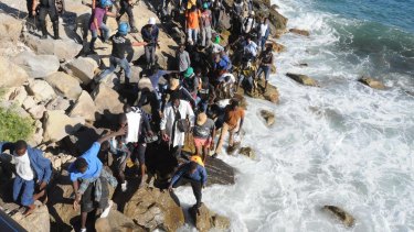 Migrants walk on the rocks as they try to get to the sea past a police cordon in Ventimiglia, an Italian town on the border with France.