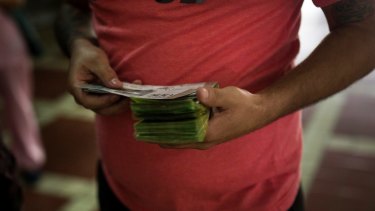 A customer counts money before purchasing animal lottery tickets in Caracas.