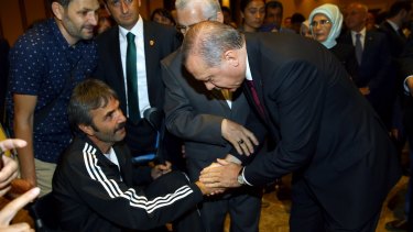 Mr Erdogan, right, shakes hands with a wounded civilian during an event to honour those killed and wounded during the failed coup.