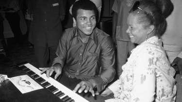 Muhammad Ali plays a few notes on the piano as singer Etta James looks on. 