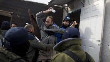A settler holding a mobile phone is arrested during the evacuation.