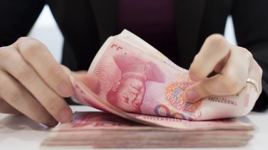 A teller counts 100 yuan notes in Beijing.