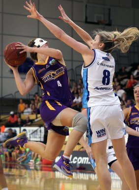 Boomer Rebecca Cole (in protective face mask) leaps into danger and Carly Wilson of the Canberra Capitals.