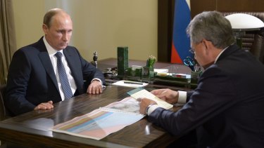 Russian President Vladimir Putin listens to Defence Minister Sergei Shoigu.