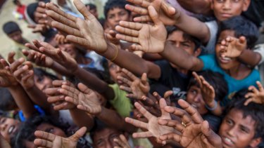 Rohingya Muslim children, who crossed over from Myanmar into Bangladesh, stretch their arms out to collect chocolates and milk distributed by Bangladeshi men.
