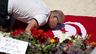 A man kisses a Tunisian flag at the site of a shooting attack on the beach in front of the Riu Imperial Marhaba Hotel in Port el Kantaoui.