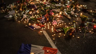 A French flag lays on the ground next to flowers and candles as a tribute to the victims of the Bastille Day Terror Attack on the Promenade des Anglais on July 16, 2016 in Nice, France.