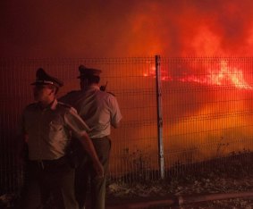 Red alert: Police officers standby while a forest fire burns the hills of Valparaiso.