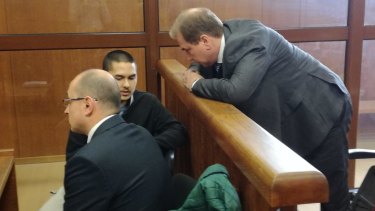John Zakhariev, centre, speaks with his Australian lawyer Jay Williams, right, in court in Sophia on Friday April 7.