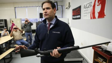 Senator Marco Rubio holds a rifle after being asked to pose for photographs during a campaign stop.