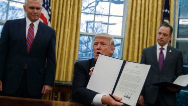 President Donald Trump (centre) shows off an executive order.
