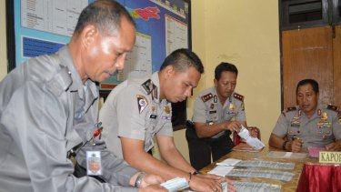 Police officers displaying six stacks of $US100 bills during a press conference by Nusa Tenggara Timur police chief Endang Sunjaya at Rote police station in June.