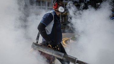 A pest control worker fumigates the grounds of an apartment block in Singapore. 