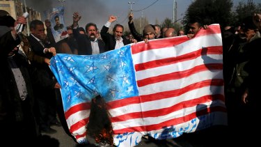 Iranian protesters chant slogans while they burn a representation of US flag on Friday.
