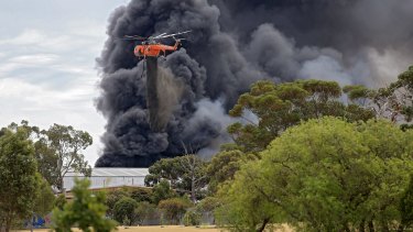A water-bombing helicopter drops its load on the massive Broadmeadows tyre fire.