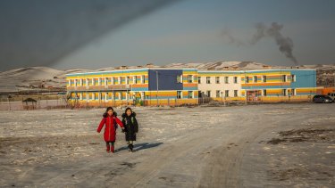 Coal smoke rises from a school's boiler as two girls walk home after class on the outskirts of Ulaanbaatar.
