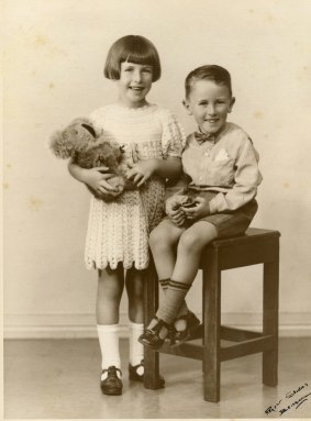 A photograph by Brisbane-based Regent Studios of a girl holding a toy koala and boy holding a toy car from the 1940s.